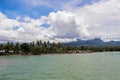 Tropical island view with palm trees and distant mountain. Warm sea with beach line and forest. Royalty Free Stock Photo