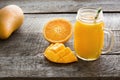 Tropical juice of mango, orange, banans fruit in jar with straw on board. Fresh healthy smoothie and drink. Royalty Free Stock Photo