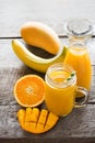 Tropical juice of mango, orange, banans fruit in jar with straw on wooden board. Royalty Free Stock Photo