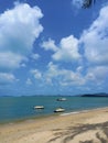 Tropical landscape. Blue sky, white clouds, beach, warm ocean and speedboats on it.