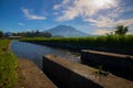 Tropical landscape during sunrise. Scenic view to Agung Volcano. River and rice fields in the village. Bali, Indonesia Royalty Free Stock Photo