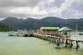 Tropical landscape with turquoise tropical sea, fishing boat, house on the water, wooden pier and Koh Chang island on horizon