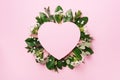 Tropical nature background with green leaves, white flowers and pink heart shaped paper for copy space. Top view. Flat lay. Royalty Free Stock Photo