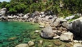 Tropical palms and stones on small beach. Many green exotic palms growing on rocky shore near calm blue sea in Hin Wong Bay on Royalty Free Stock Photo