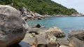 Tropical palms and stones on small beach. Many green exotic palms growing on rocky shore near calm blue sea in Hin Wong Bay on Royalty Free Stock Photo