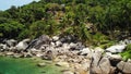 Tropical palms and stones on small beach. Many green exotic palms growing on rocky shore near calm blue sea in Hin Wong Bay on Royalty Free Stock Photo