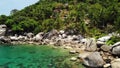 Tropical palms and stones on small beach. Many green exotic palms growing on rocky shore near calm blue sea in Hin Wong Bay on Royalty Free Stock Photo