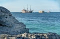 Tropical paradise. View of bright blue ocean with old vintage ship and yachts and big rocky shore Royalty Free Stock Photo