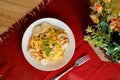 Tropical Pasta Salad With Mix Meat olive with shrimp and prawn served in bowl with flowers and fork isolated on red napkin side Royalty Free Stock Photo