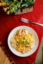 Tropical Pasta Salad With Mix Meat olive with shrimp and prawn served in bowl with flowers and fork isolated on red napkin top Royalty Free Stock Photo