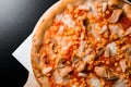 Tropical pizza with tomato sauce, mozzarella cheese, sweet corn, chicken and pineapple isolated over black background