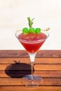 Tropical red cocktail with green sugar cherries on the wooden table at the beach and ocean Royalty Free Stock Photo