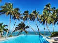 Tropical resort's pool with lagoon view and palms on a sunny day Royalty Free Stock Photo