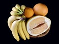 Tropical, ripe fruits in a bowl, on a black background. Yellow citrus fruits and bananas on a plate. Healthy diet: pamelo,