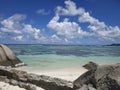 Tropical shore at Ladigue Seychelles with clouds and light blue transparent water