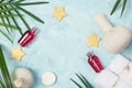 Tropical spa mockup: white towels, red shampoo bottles, Thai masage bags, golden stars and green fern leaves on blue background