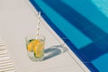 Tropical sparkling cocktail by the pool. The picture of glass with lemon and cucumber lemonade fruit cocktail standing Royalty Free Stock Photo