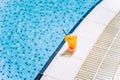 Tropical sparkling cocktail by the pool. The shot of glass with orange lemonade fruit cocktail standing near the Royalty Free Stock Photo