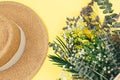 Tropical straw bag, summer flowers in bouquet on yellow background. Fashion accessories. Flat lay, close up. Summer, vacation