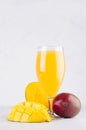 Tropical summer juice of ripe fresh mango with pulpy chopped slice on soft light elegant white background, vertical. Royalty Free Stock Photo