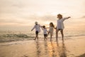 Happy family having fun running on a sandy beach at sunset time Royalty Free Stock Photo