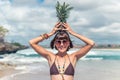 Tropical summer woman with pineapple on her head. Outdoors, ocean, nature. Bali island paradise.