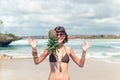 Tropical summer woman with pineapple on her head. Outdoors, ocean, nature. Bali island paradise.