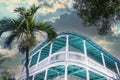 Tropical turquoise building with balcony around it against stormy sky with palm tree - looking up at an angle - perspective