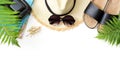 Tropical vacation pattern. Straw beach sunhat, sun glasses, beach slaps, leaf of fern on white background. Top view with copy spac