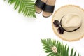 Tropical vacation pattern. Straw beach sunhat, sun glasses, beach slaps, leaf of fern on white. Top view with copy space. Summer