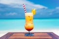 Tropical vibrant banana cocktail with straw on the wooden table at the beach with ocean