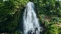 Tropical waterfall flowing down on sunny day. Mountain water stream falling Royalty Free Stock Photo