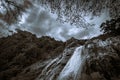 Tropical waterfall in the rain forest. Black white cloudy sky with trees and rocky waterfall Royalty Free Stock Photo