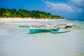 Tropical white sand beach with green palm trees and parked fishing boats in the sand. Exotic island paradise Royalty Free Stock Photo