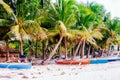 Tropical white sand beach with green palm trees and parked fishing boats in the sand. Exotic island paradise Royalty Free Stock Photo