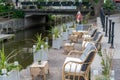 Selective focus view of an idyllic waterfront patio of a restaurant with lounge chairs and small tables