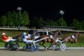 Trotting racehorses and rider on a stadium track.