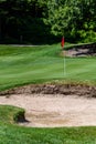 Trouble on the golf course, sand trap protecting a golf green with trees in the background, includes pin with red flag and golf ca Royalty Free Stock Photo