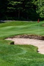 Trouble on the golf course, sand trap protecting a golf green with trees in the background, includes pin with red flag and golf ca Royalty Free Stock Photo