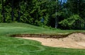 Trouble on the golf course, sand trap protecting a golf green with trees in the background