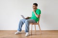 Troubled arab man sitting on chair with laptop, thinking over solution to problem against white wall, copy space Royalty Free Stock Photo