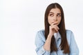 Troubled, distressed serious-looking pensive brunette woman in denim jacket, touching lip, looking upper left corner