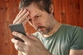 Troubled man receiving unpleasant sms message notification on mobile smart phone