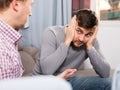 Troubled man talking with friend on sofa Royalty Free Stock Photo