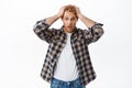 Troubled redhead man, holding hands on head and staring shocked and puzzled, feeling nervous, have problem, forgot Royalty Free Stock Photo