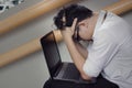 Troubled stressed Asian business man with laptop covering face with hands on staircase of office. Royalty Free Stock Photo