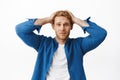 Troubled and worried young redhead man, look distressed, holding hands on head indecisive and nervous, panicking, having Royalty Free Stock Photo