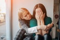 Troubled young girl comforted by her friend. Woman supporting the girl