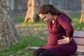 Troubled young pregnant woman on a park bench