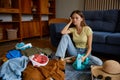 Troubled young woman preparing luggage for travel at home